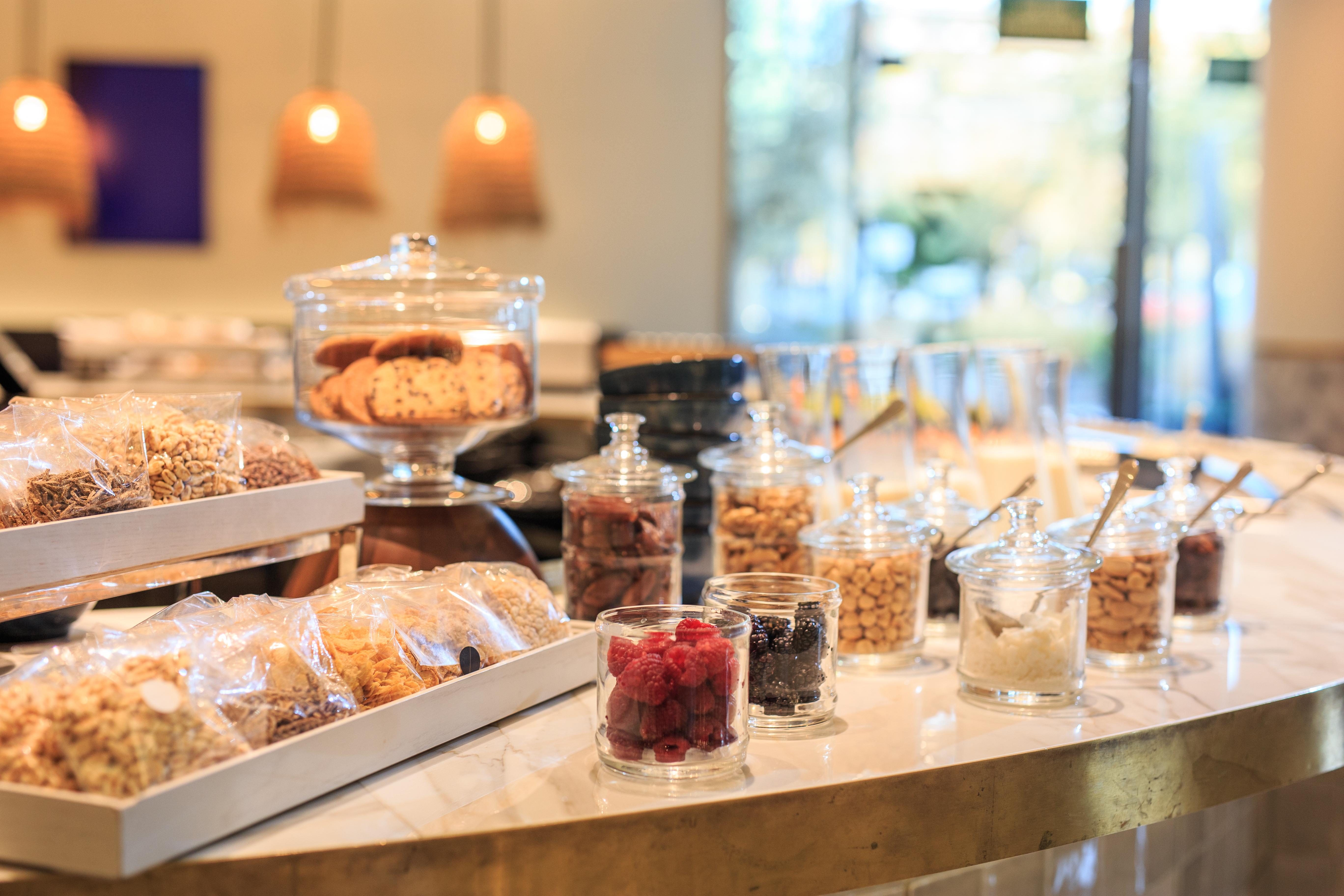 Hotel Grand Hyatt Barcelona Exteriér fotografie The photo displays a variety of snacks and treats arranged on a countertop. There are several jars filled with different types of items, including colorful candies, nuts, and dried fruits. A glass container holds cookies, and there are neatly package