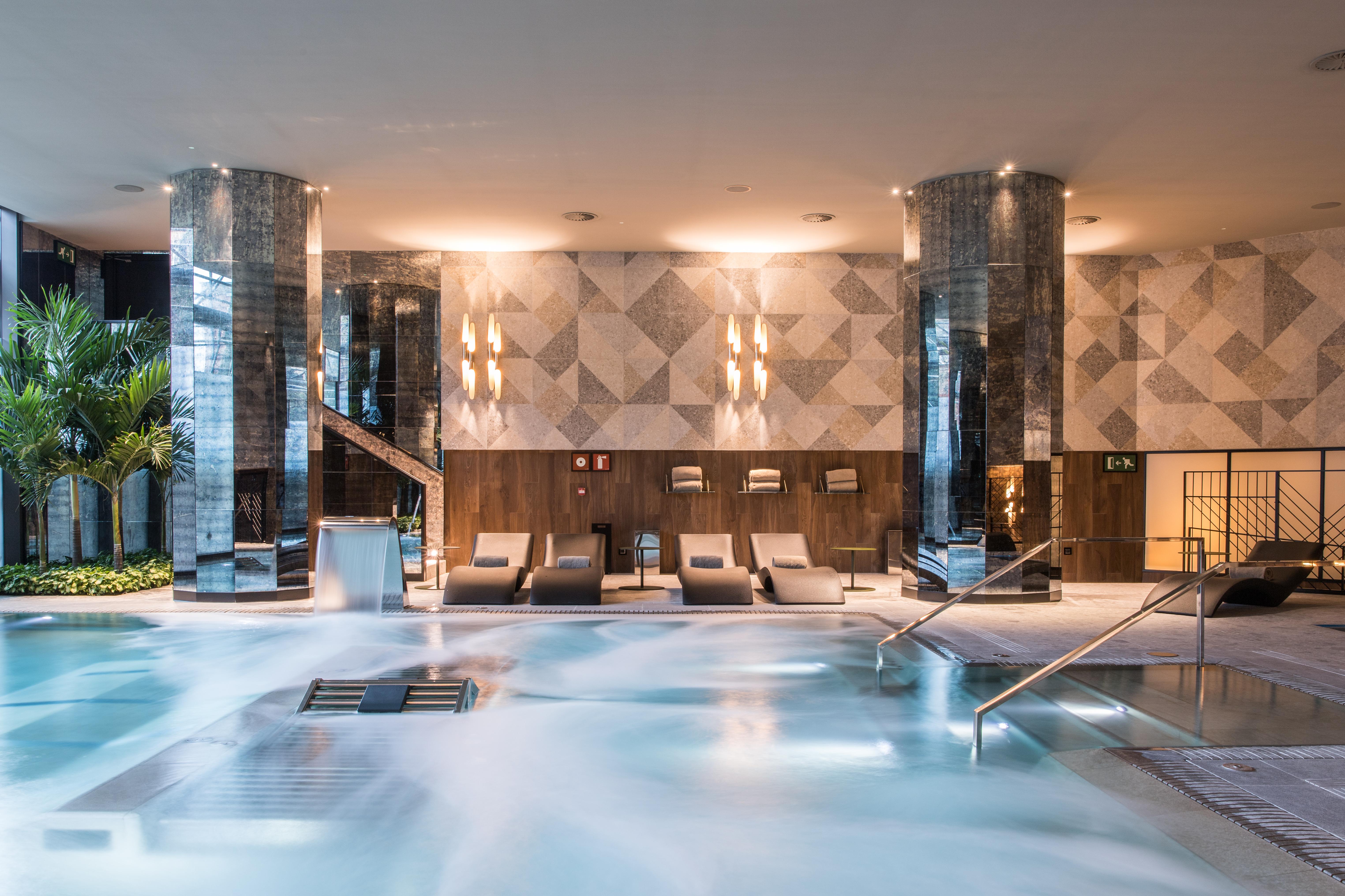 Hotel Grand Hyatt Barcelona Exteriér fotografie The photo shows a sophisticated spa area featuring a large, inviting pool with a calm, relaxing atmosphere. The pool area is surrounded by elegant columns and has a modern design. There are comfortable lounge chairs positioned nearby, and the lightin